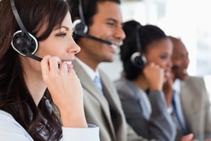 Young employee working with a headset and accompanied by her team
