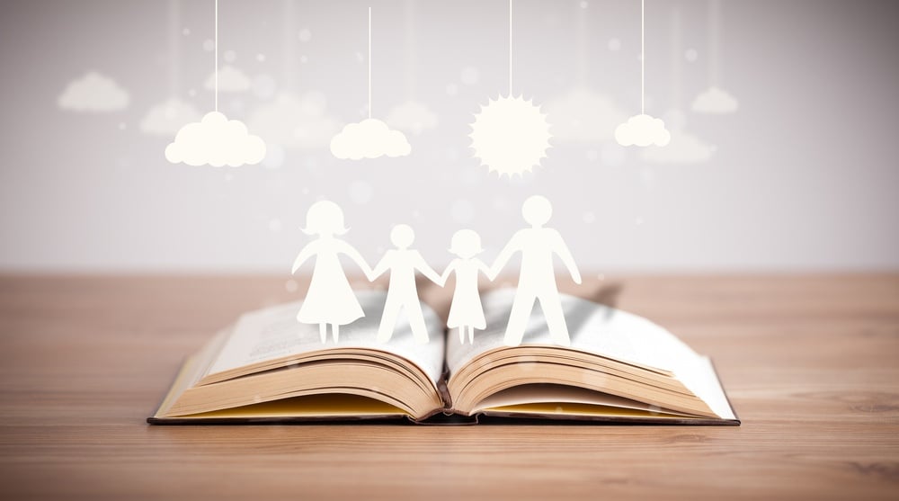 Cardboard figures of the family on opened book. The symbol of unity and happiness