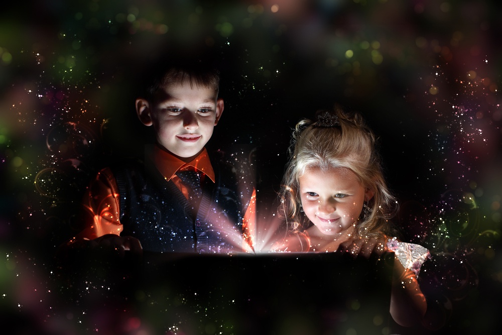 Children opening a magic gift box with lights and shining around